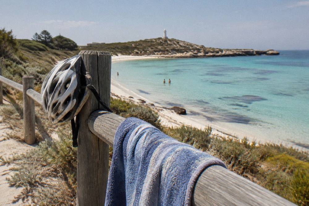 A bicycle leaning against a fence above a sheltered sandy bay on Rottnest Island