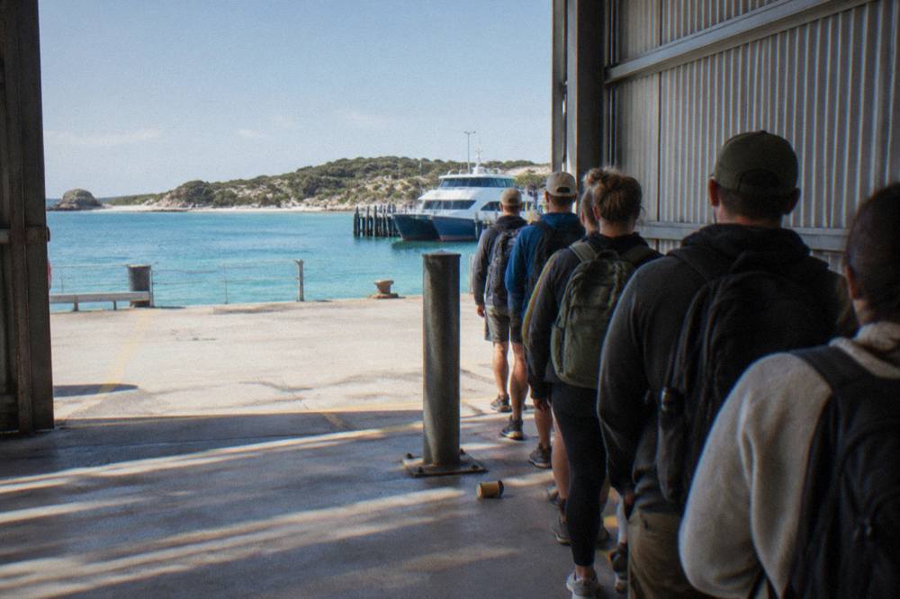 Queue of travellers with day packs waiting at a ferry terminal gate in morning light