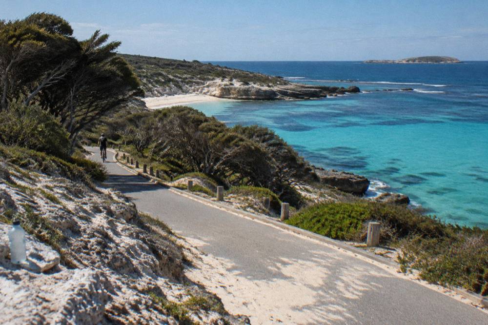 A coastal cycle path curving along a Rottnest headland above turquoise water