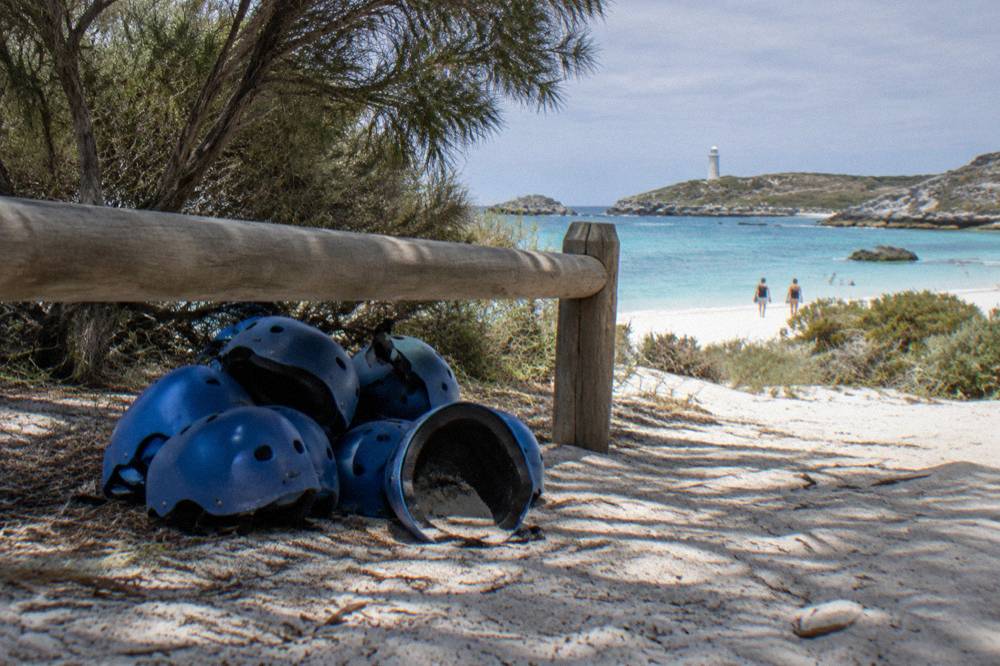 Bicycles leaning against a low fence near the sand at a Rottnest Island bay
