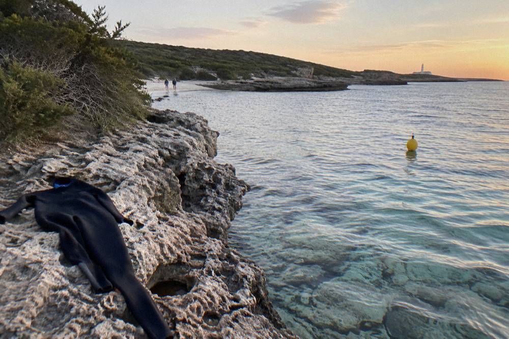A marked snorkel trail buoy floating over calm reef water near a rocky southern Rottnest bay