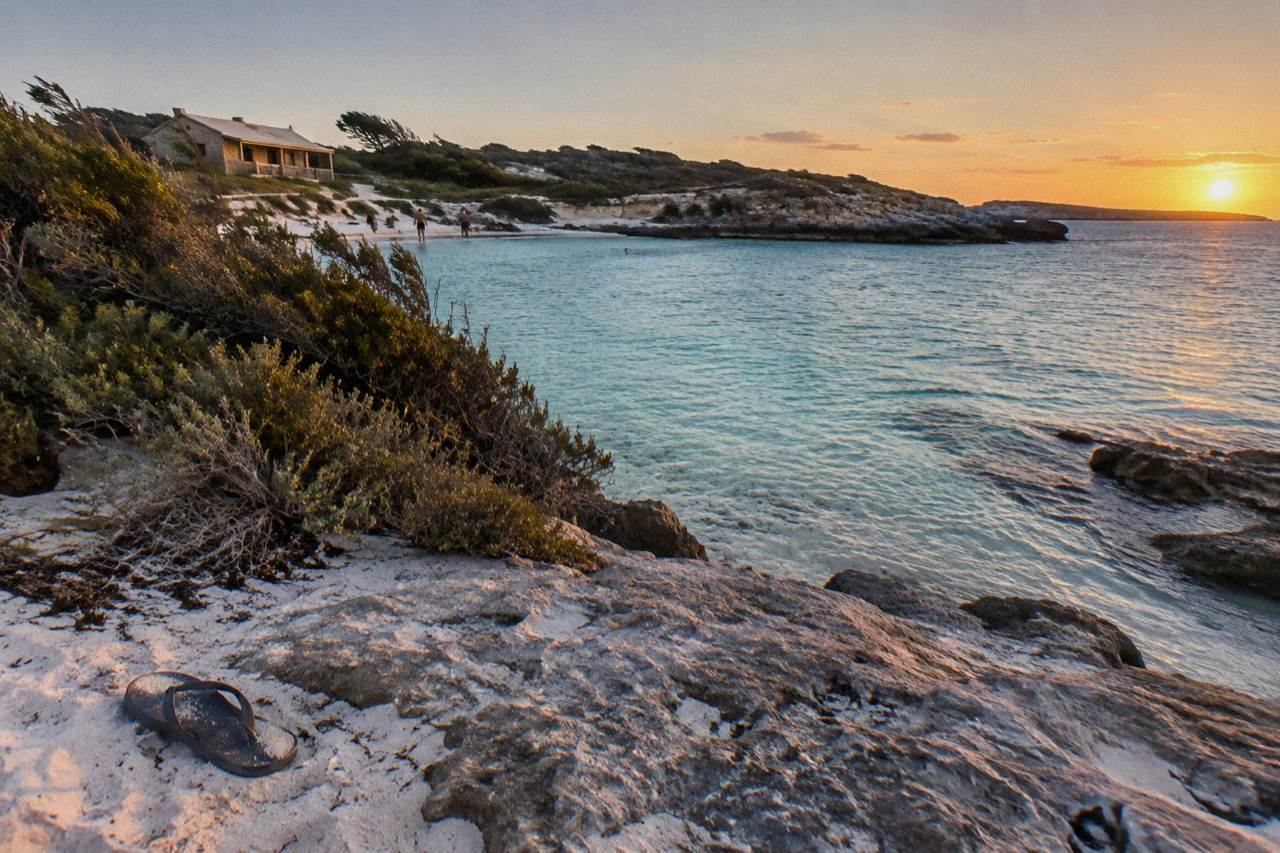 Turquoise water and white sand at a sheltered Rottnest Island bay with low coastal scrub