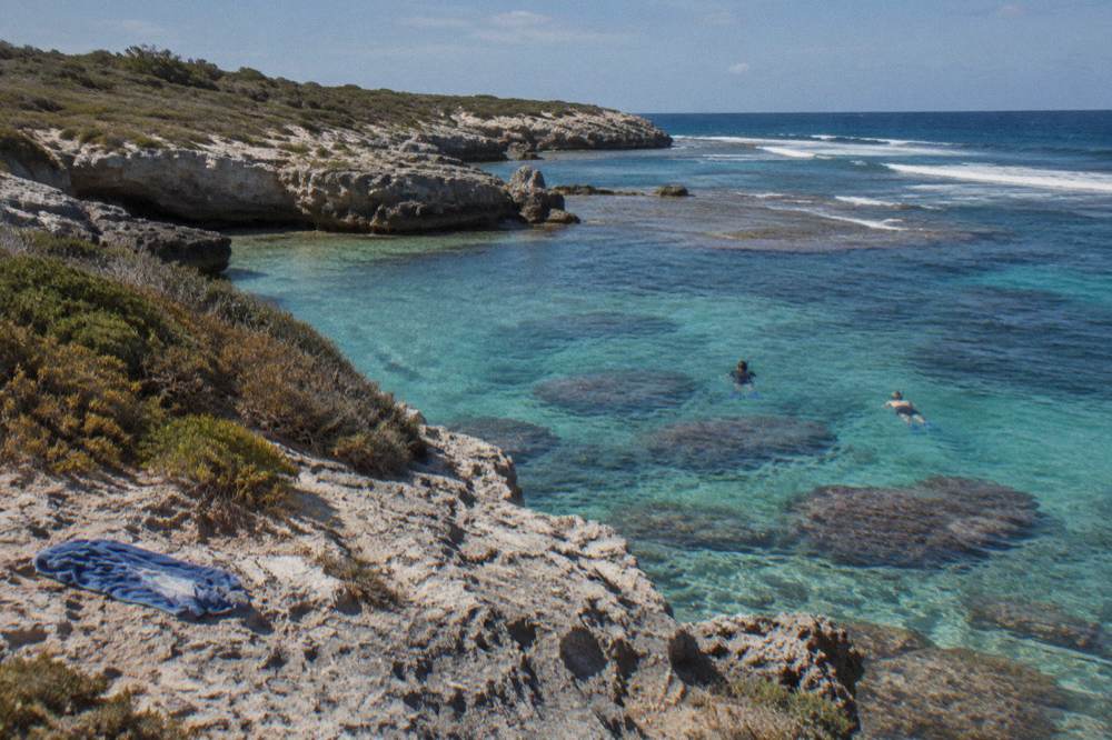 Snorkellers floating over a shallow coral reef in clear turquoise water