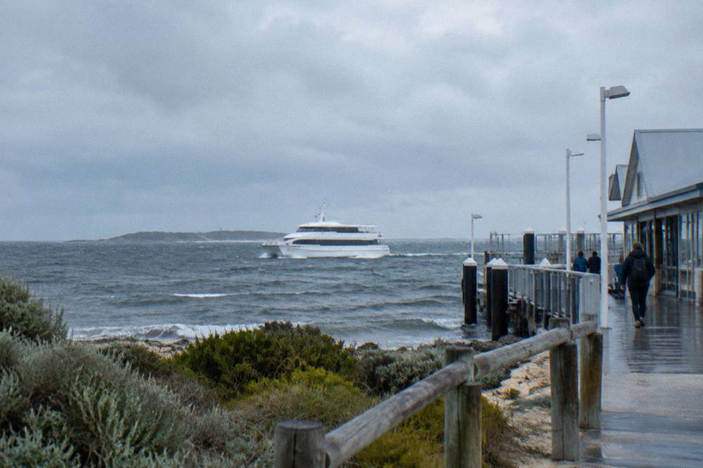 A passenger ferry cutting across open water towards an island on the horizon