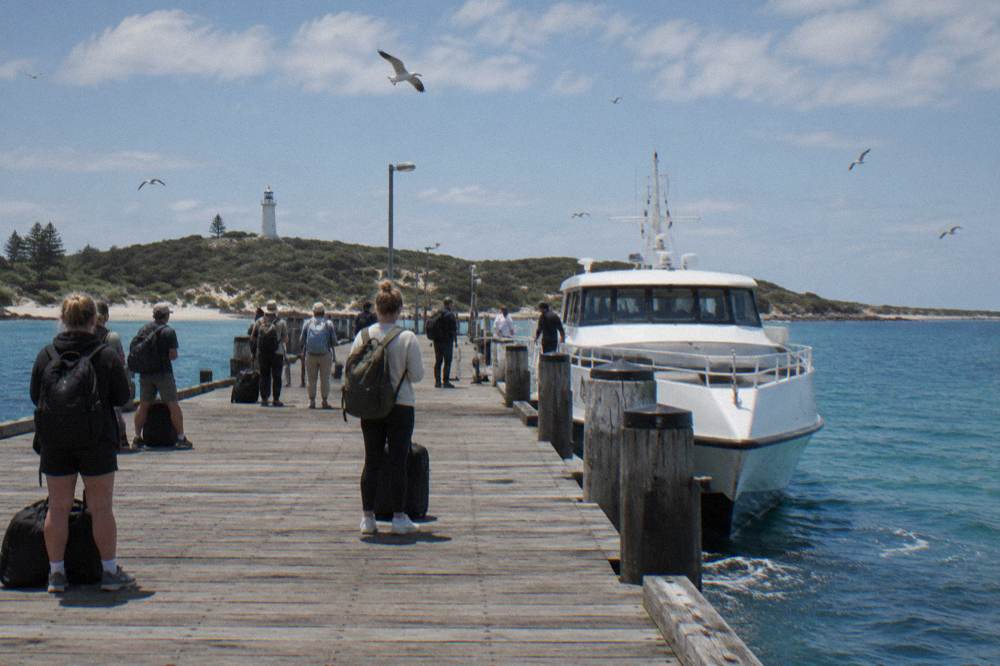 A ferry arriving at a busy island jetty with cyclists waiting to disembark