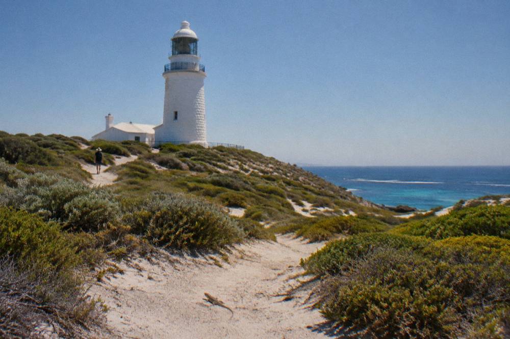 A white lighthouse above low coastal scrub on Rottnest Island