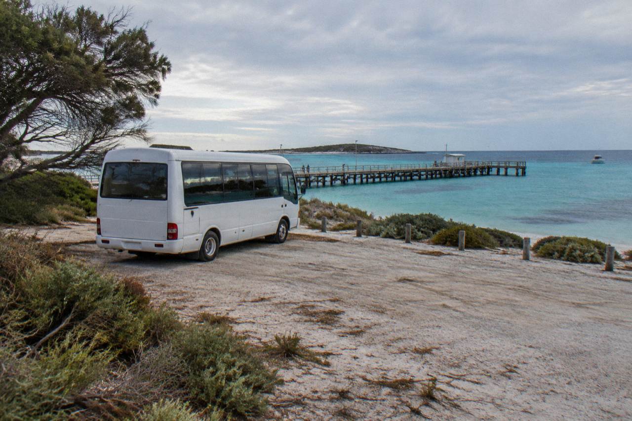 A tour bus parked beside the turquoise water of Thomson Bay at Rottnest Island
