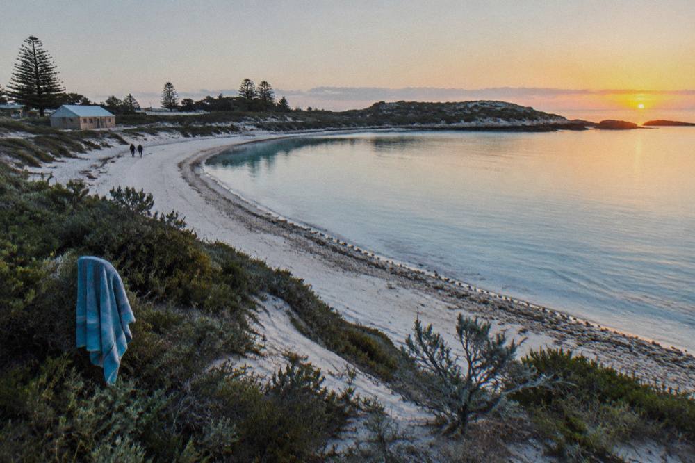 A curve of pale sand and clear turquoise water at a sheltered Rottnest Island bay