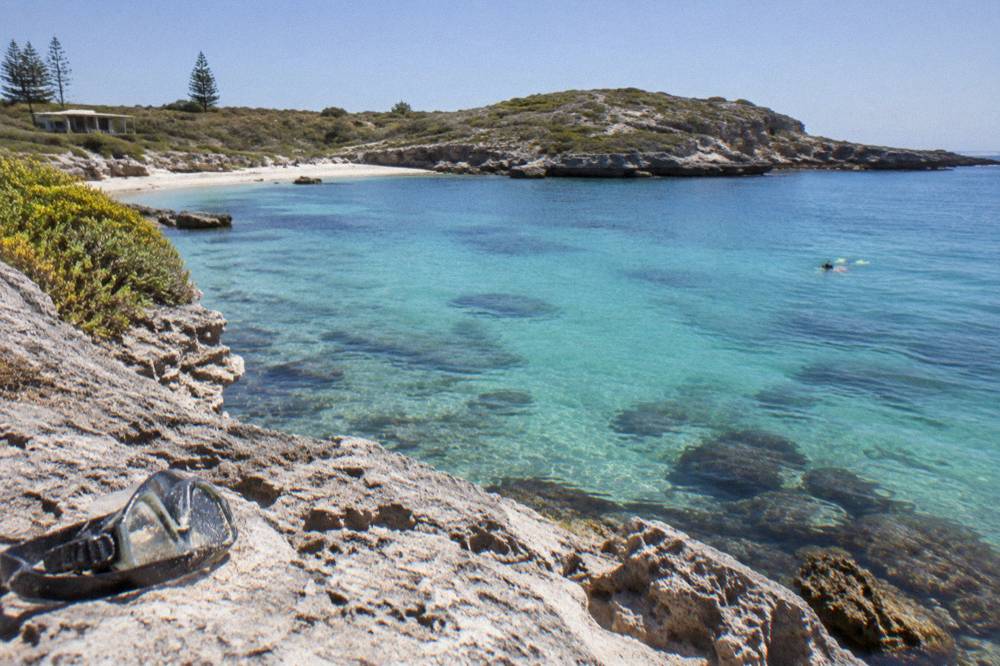 Shallow clear water over reef at a sheltered swimming bay with sandy edge
