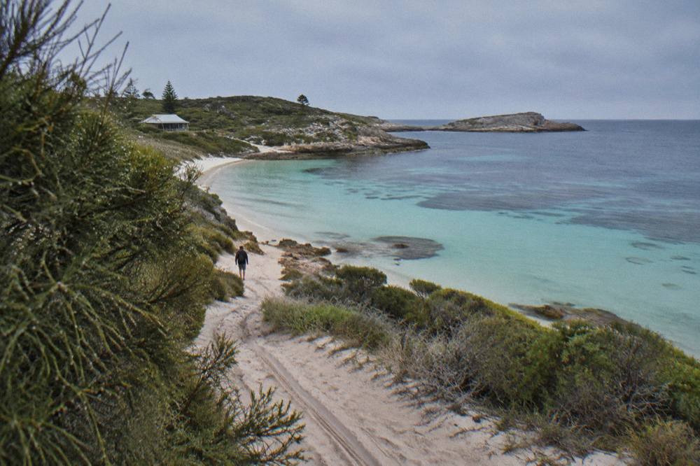 A cyclist riding along a coastal path with calm turquoise bays on Rottnest Island