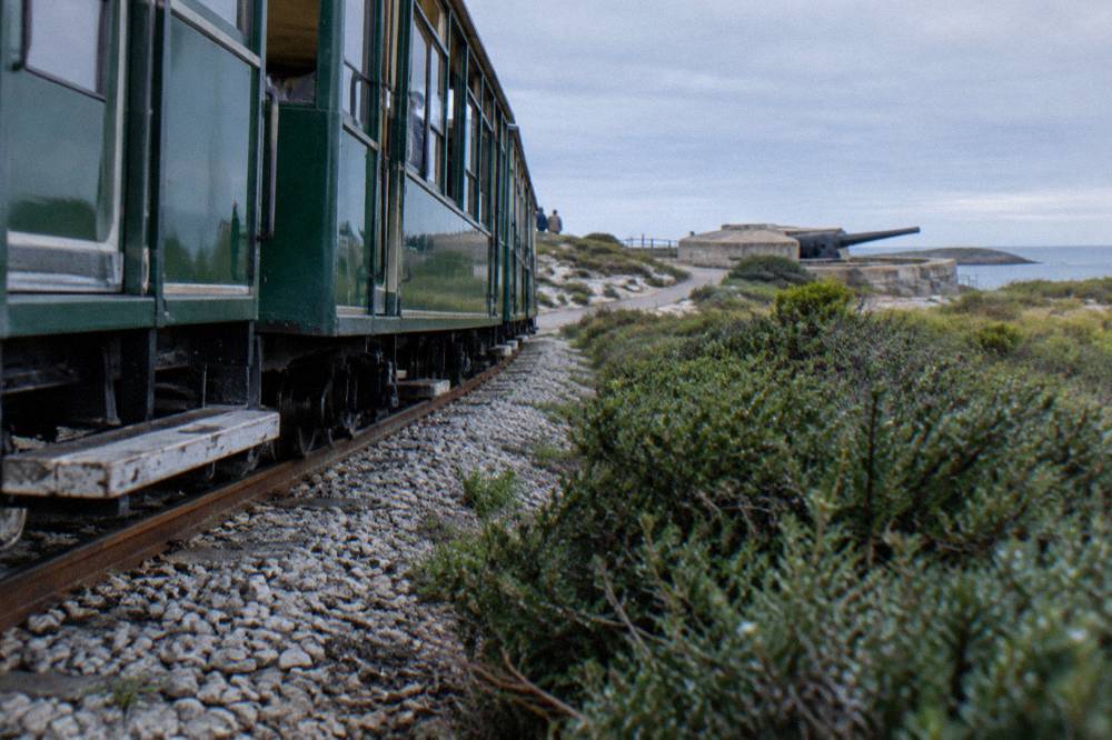 Heritage train carriage on the Rottnest Island railway line passing through low coastal scrub