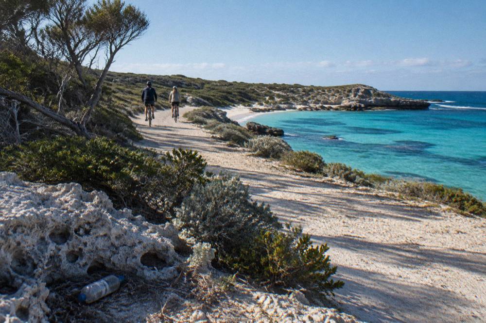 Cyclists on a coastal path above turquoise water on Rottnest Island