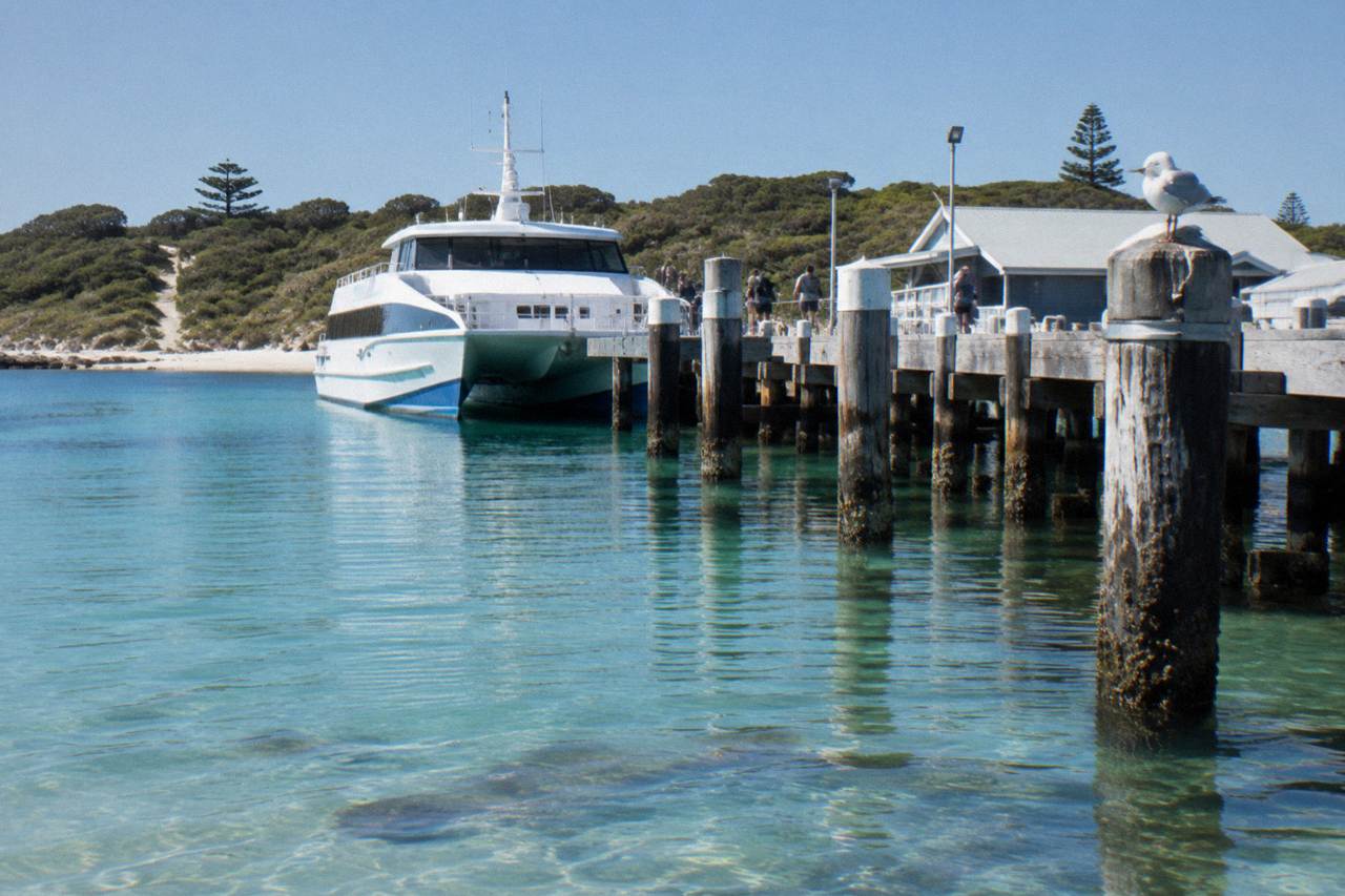 Ferry moored at a jetty on Rottnest Island with calm turquoise water in Thomson Bay