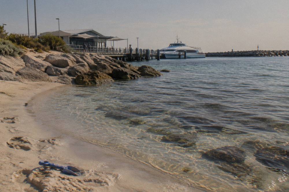 A calm sheltered bay with clear shallow water over reef and a sandy beach curve