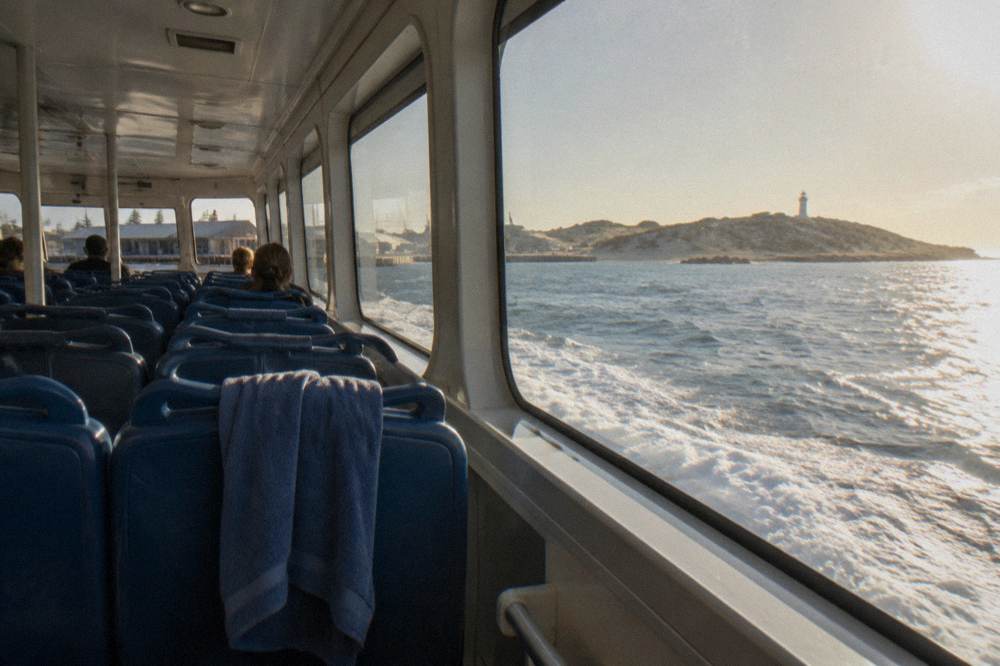 Ferry cabin interior with rows of seats and windows looking out over water