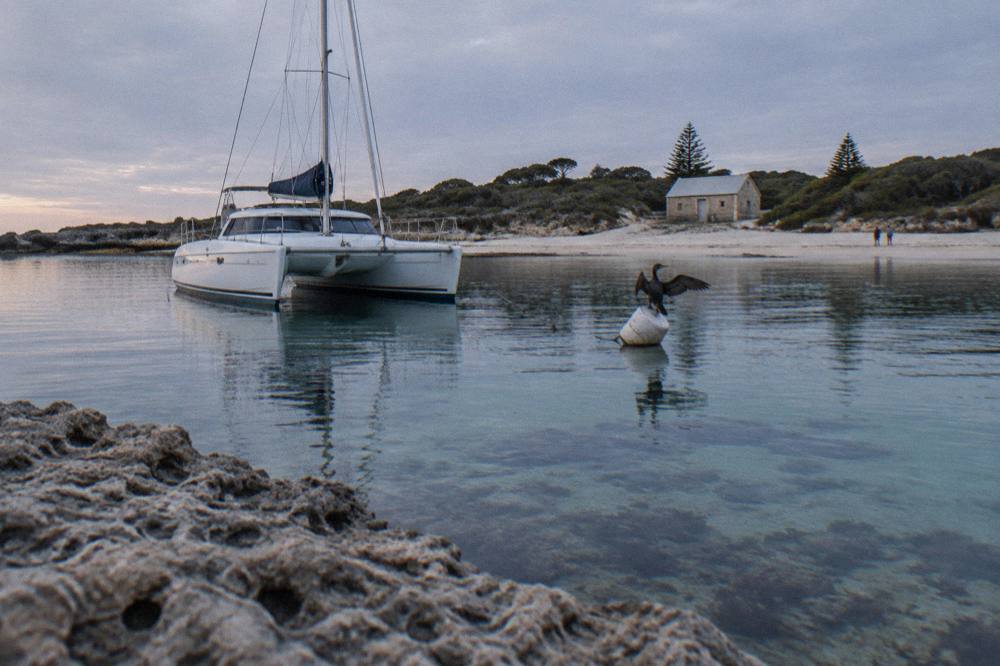 A catamaran moored in a calm bay with reef visible below the surface
