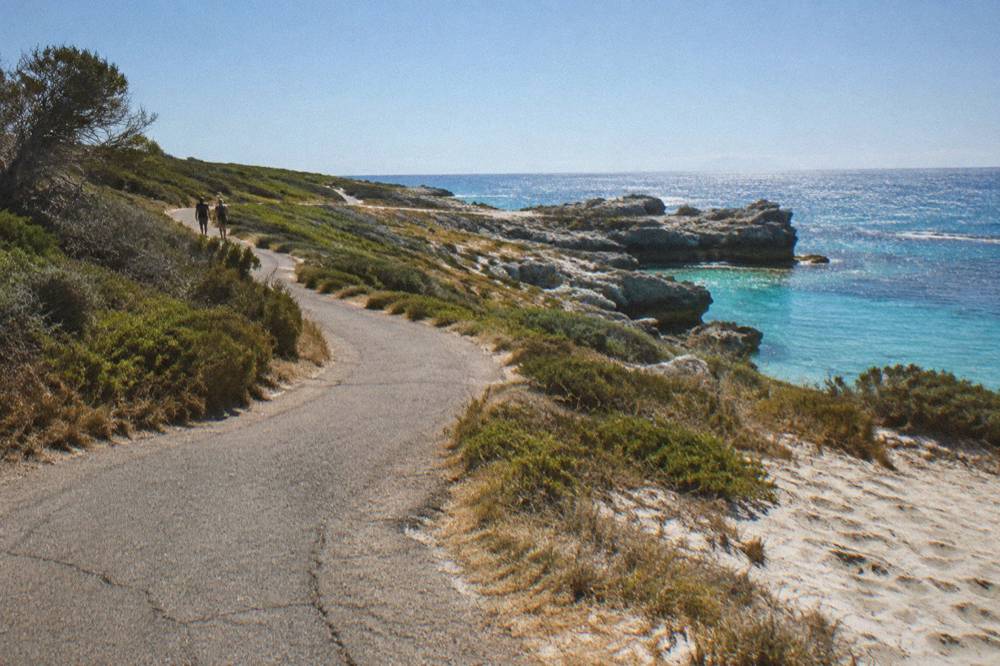 Cyclists riding a coastal path under a bright blue summer sky