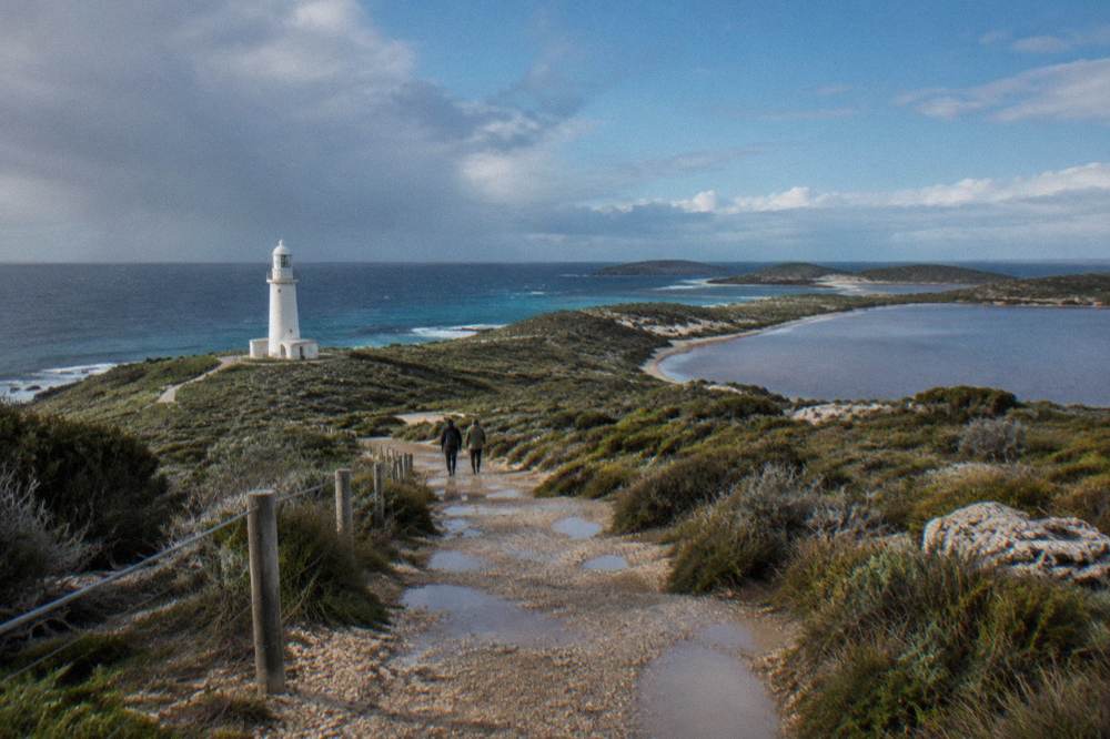 Coastal walking trail along grassy dunes under a partly cloudy sky