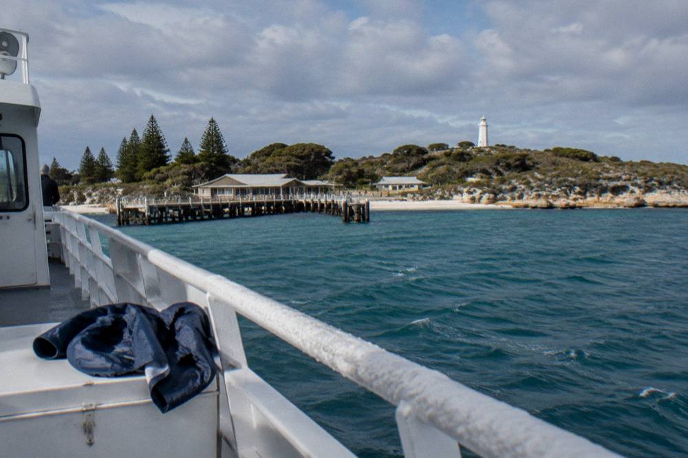 A ferry cruising across open water toward an island coastline on a sunny day