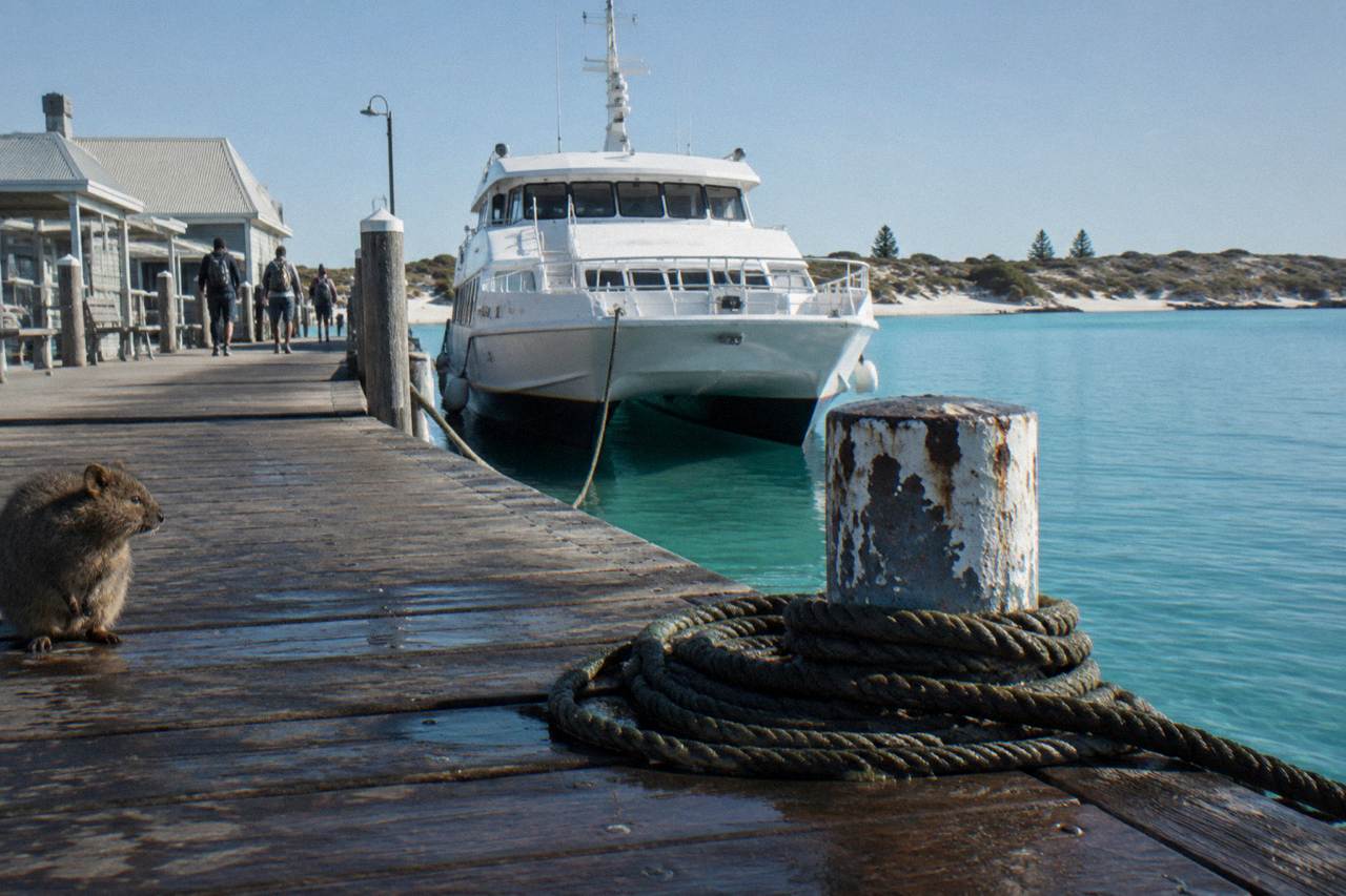 A passenger ferry moored at a jetty on Rottnest Island with calm turquoise water behind it