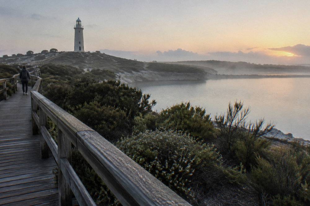 Stone lighthouse tower seen across flat salt lakes and low heathland