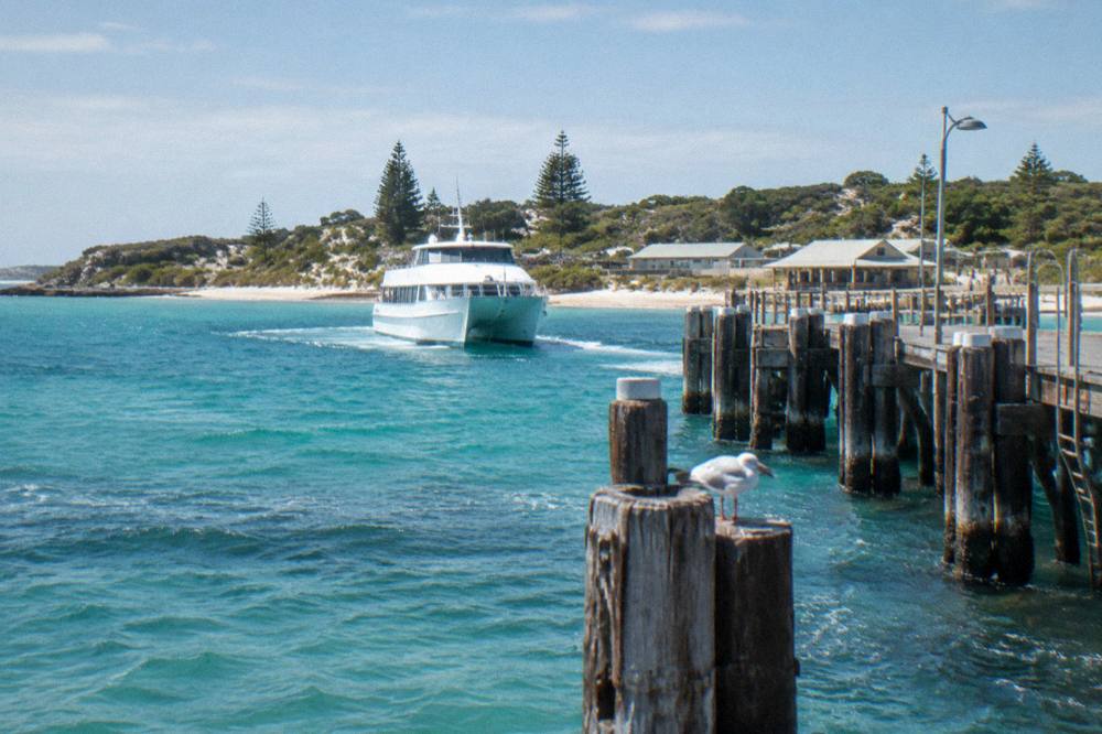 Ferry approaching a wooden jetty in a sheltered bay with clear water